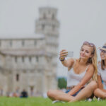 Young teen girls traveler tourist before Pisa tower selfie for smartphone picture or video.